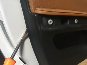 Screwdriver wedged on lower part of BMW door panel to remove it.