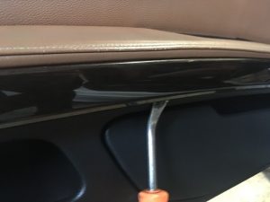  Bmw E92 Drivers Door Center Trim being removed with a flat screwdriver.