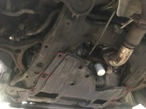 Honda accord engine and transmission splash shield underneath the car.