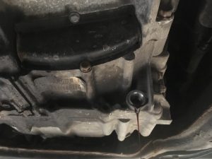 honda automatic transmission with drain plug removed and transmission fluid draining. 