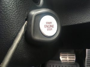 A flat screwdriver removing engine push start button on VW Gti.
