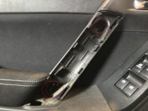 A Subaru door with door pull handle removed revealing door panel screws.