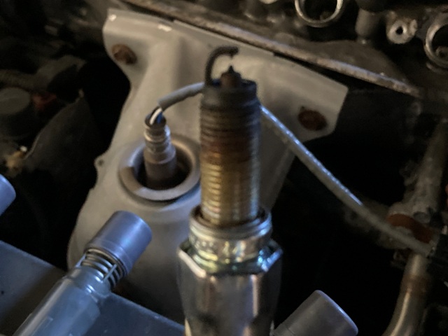 A old spark plug removed from Acura 2.0 liter engine, spark plug is slugged and shows wear.