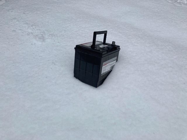 Car battery abandoned in a field of snow.